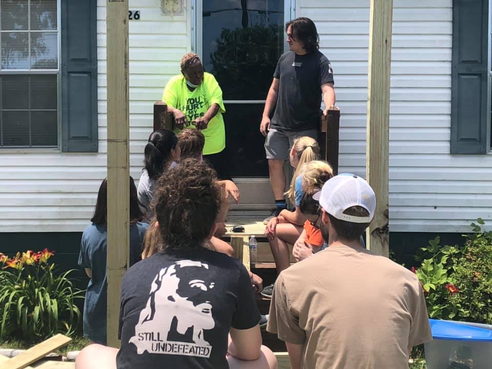 Group of young volunteers working on front porch and ramp on a house