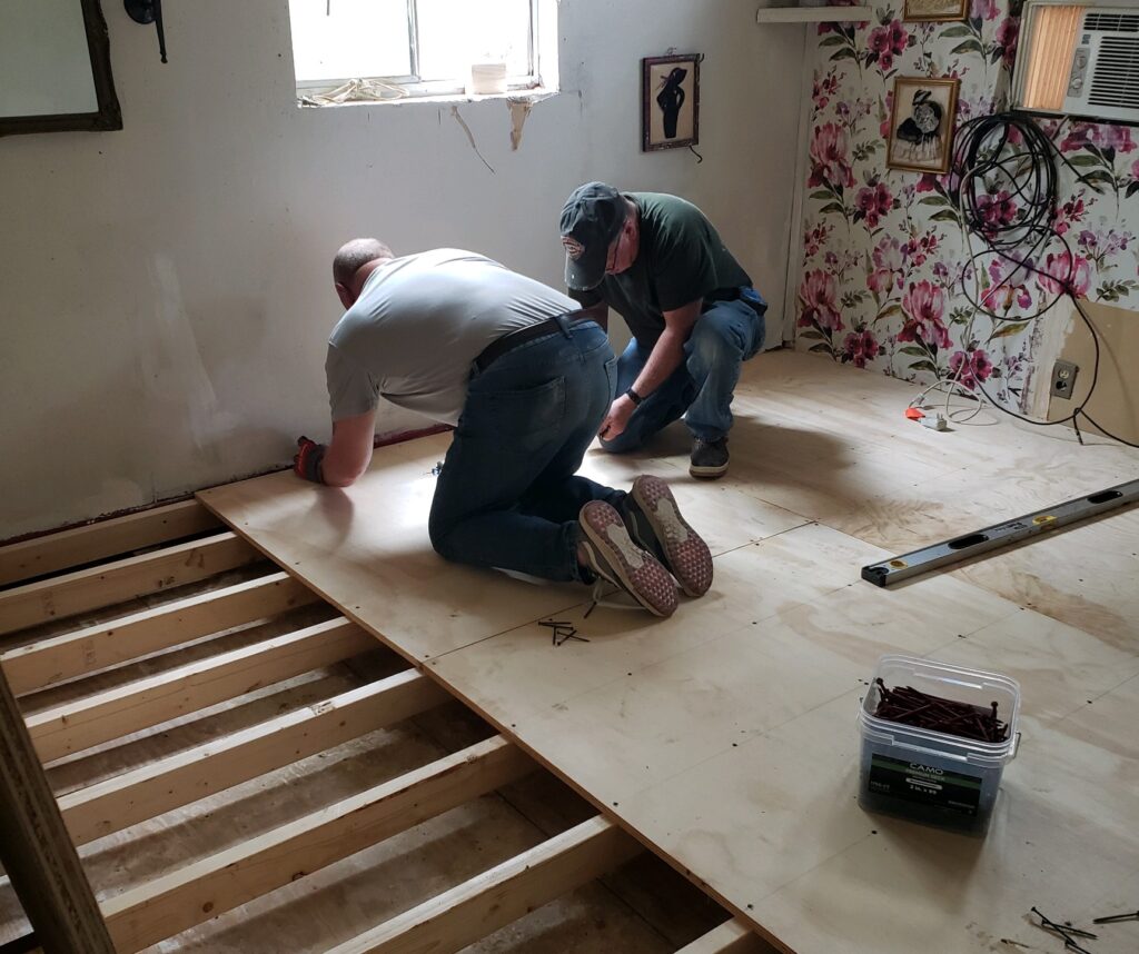 Two men volunteer with Interfaith replacing a floor in a house located in Lancaster, Virginia.